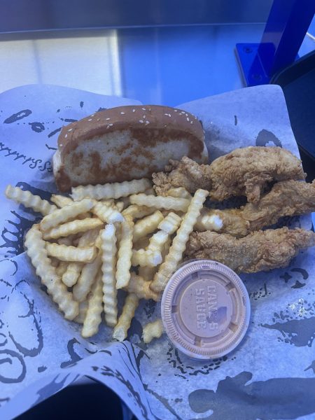 A photo of french fries, toast, and chicken tenders with a Cane's sauce container.