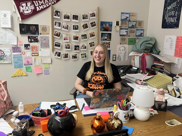 This photo features English Teacher and Drama Club Director Ms. Kari Collins sitting at her desk, smiling.