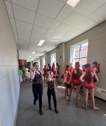 Legacy dancers in 'I Did It Again', a Britney Spears-themed Pom dance (red), wait backstage in anticipation for their number while dancers from other studios go back to the dressing room.